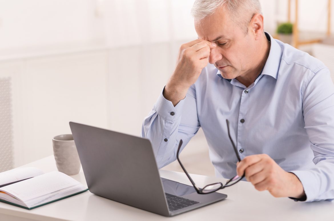 Entrepreneur man massaging nose while using laptop Entrepreneur Anxiety